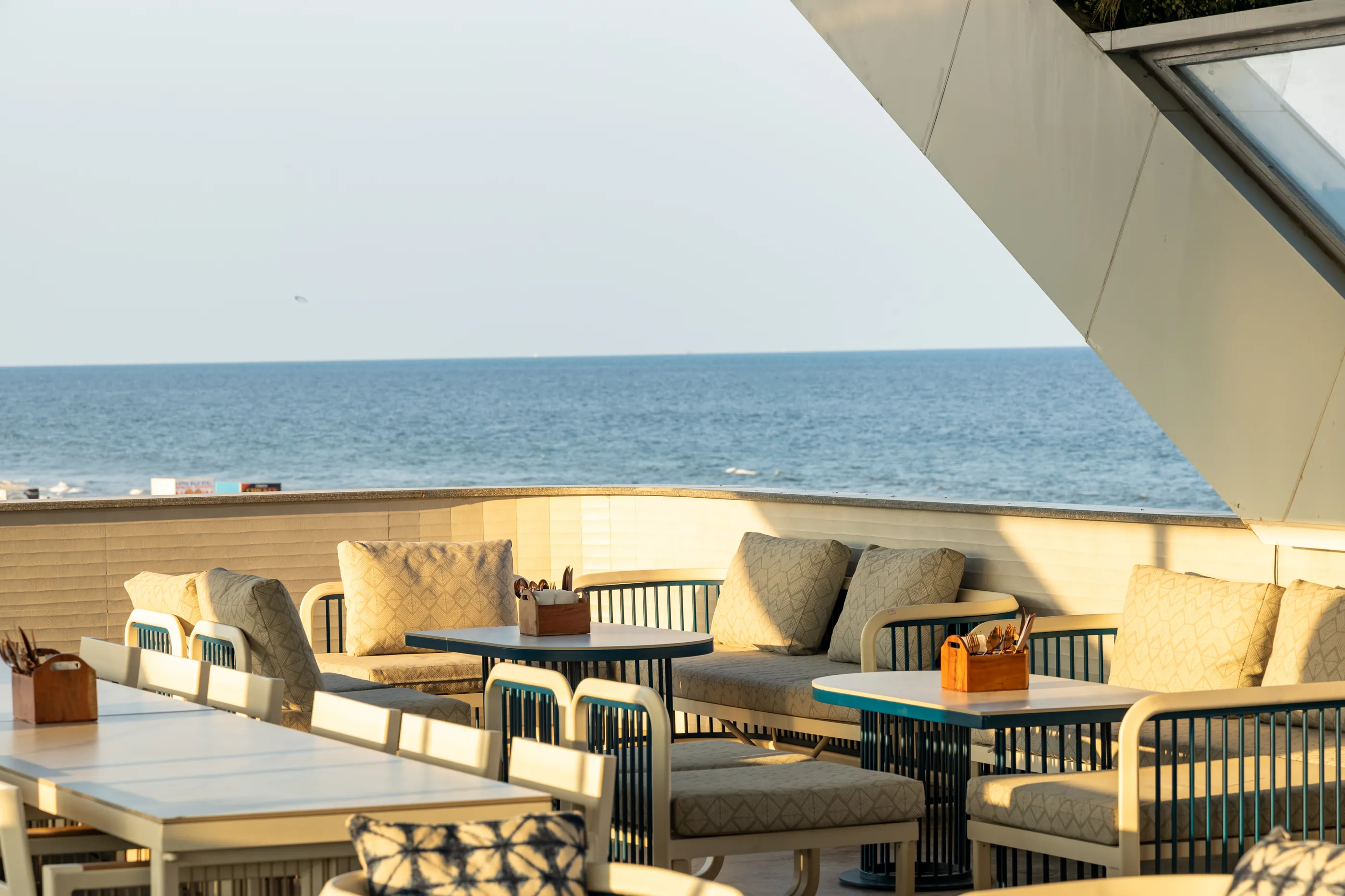 The sea-facing terrace at Mirabilis in afternoon light, the white angular wing overhead and the Bay of Bengal beyond
